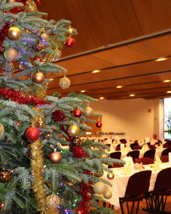 Weihnachtsfeier 2023 | © RÖSLE GROUP Ein festlich geschmückter Weihnachtsbaum und dekorierte Tische im Hintergrund | © RÖSLE GROUP