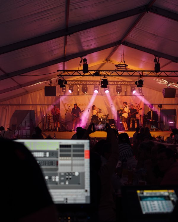 Zwei Personen am Mischpult, im Hintergrund ist die musizierende Band zu sehen | © RÖSLE GROUP