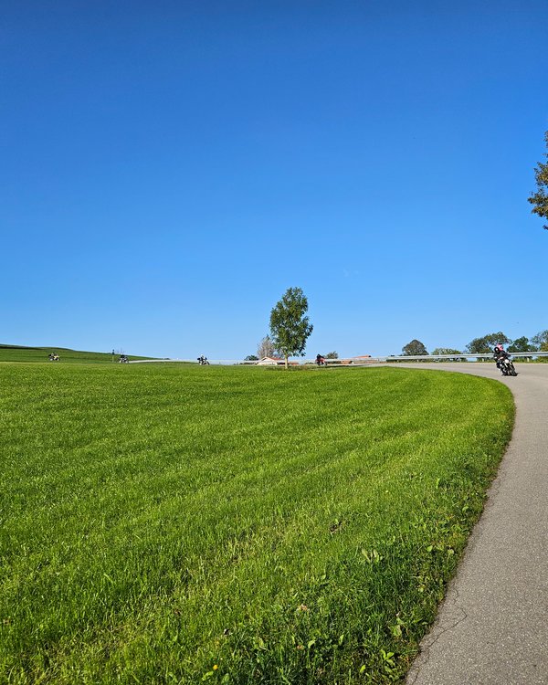 Motorrad-Ausfahrt 2024 | © RÖSLE GROUP Eine Gruppe Motorradfahrer, die bei blauem Himmel und grünen Wiesen um eine Kurve fahren | © RÖSLE GROUP