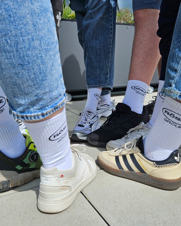 Team-Socken für die Azubis | © RÖSLE GROUP Die Azubis stehen in einem Kreis auf einem gepflasterten Boden, die Füße sind zur Mitte ausgerichtet und zeigen weiße RÖSLE GROUP-Socken, es sind nur die Füße zu sehen | © RÖSLE GROUP