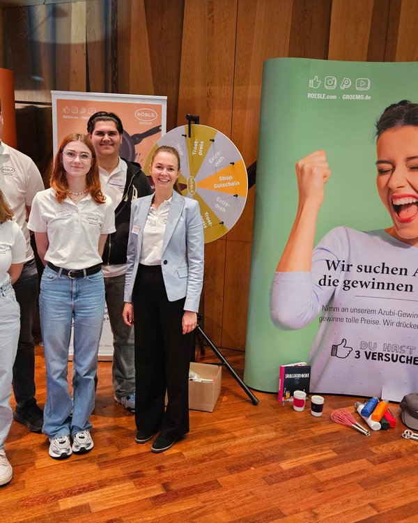 Ausbildungsmesse Marktoberdorf 2025 | © RÖSLE GROUP Vier Azubis und die Verantwortliche für die Ausbildung stehen nebeneinander auf dem Messestand und lächeln zur Kamera | © RÖSLE GROUP