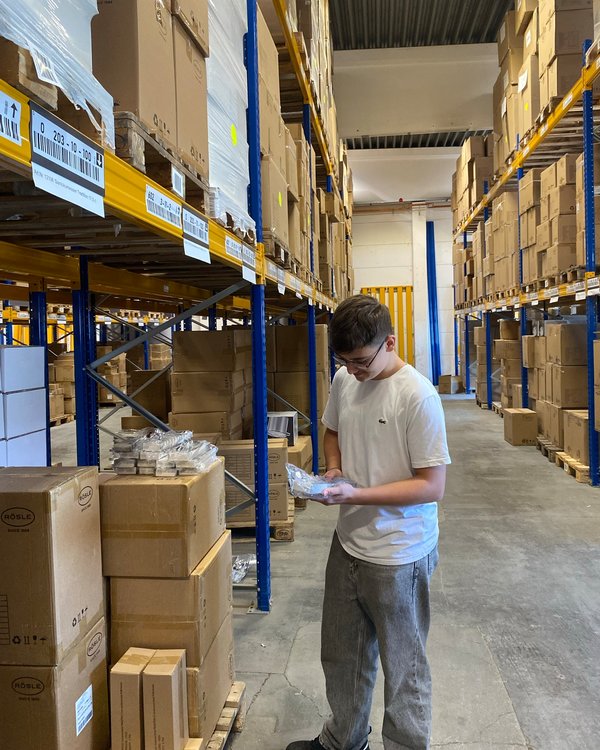 Ein Junge steht in einem Lager und checkt einen Artikel auf Richtigkeit | © RÖSLE GROUP