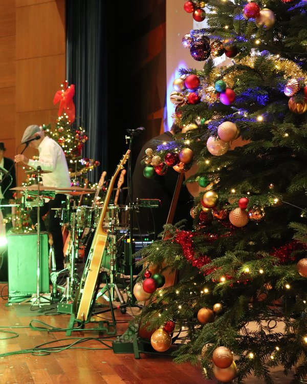 Ein Christbaum steht auf einer Bühne der hell beleuchtet und geschmückt ist. Neben dem Christbaum stehen Instrumente. | © RÖSLE GROUP