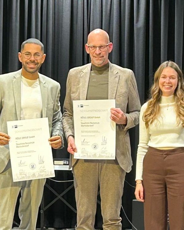 5 Menschen stehen in einer Reihe. Es sind 2 Männer und 3 Frauen. Sie lächeln alle in die Kamera und die beiden Männer halten Urkunden in die Kamera. Sie sind alle formell angezogen | © RÖSLE GROUP