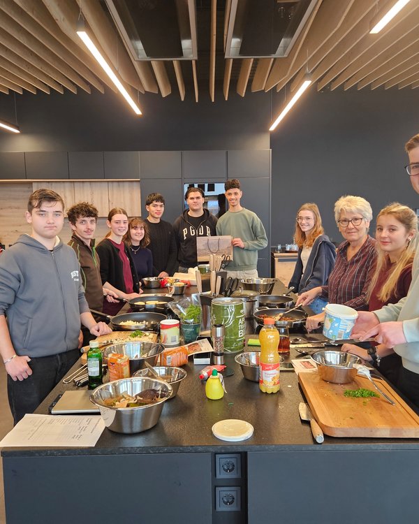 Viele Leute stehen um eine Arbeitsplatte herum. Sie sind alle mit kochen beschäftigt | © RÖSLE GROUP